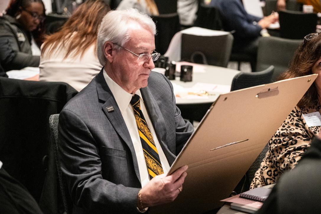 Chancellor writes on a large notepad at the Strategic Plan event.